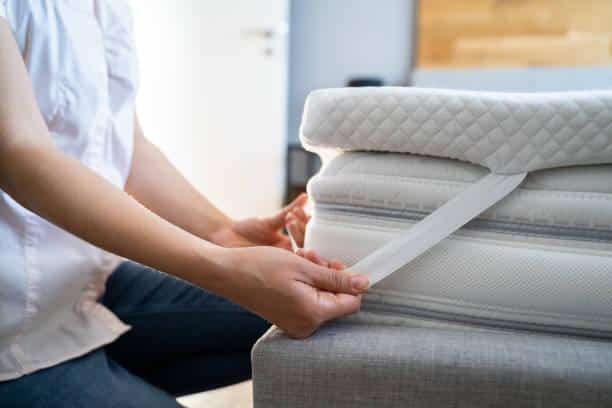 Woman setting up mattress topper on memory foam mattress