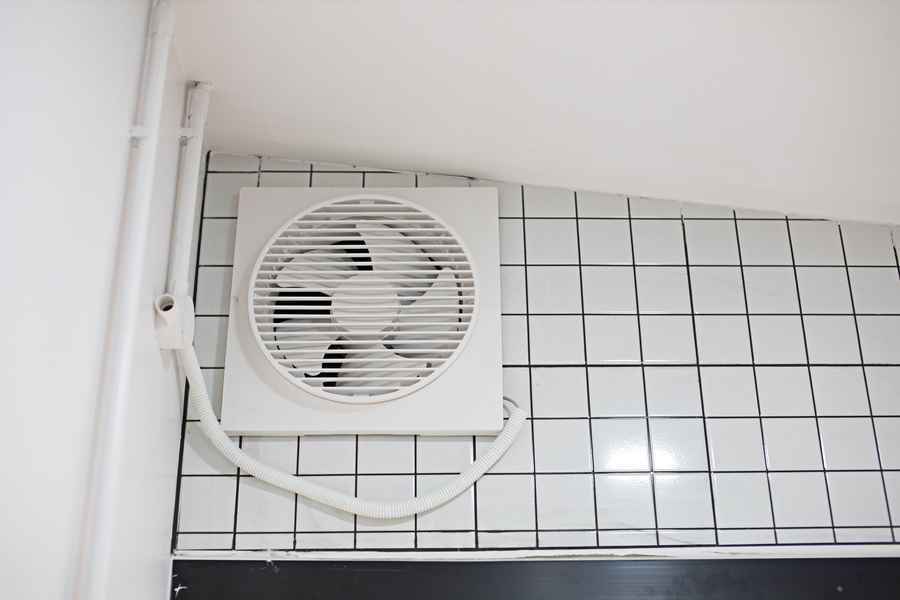 White plastic bath exhaust fan mounted in the bathroom
