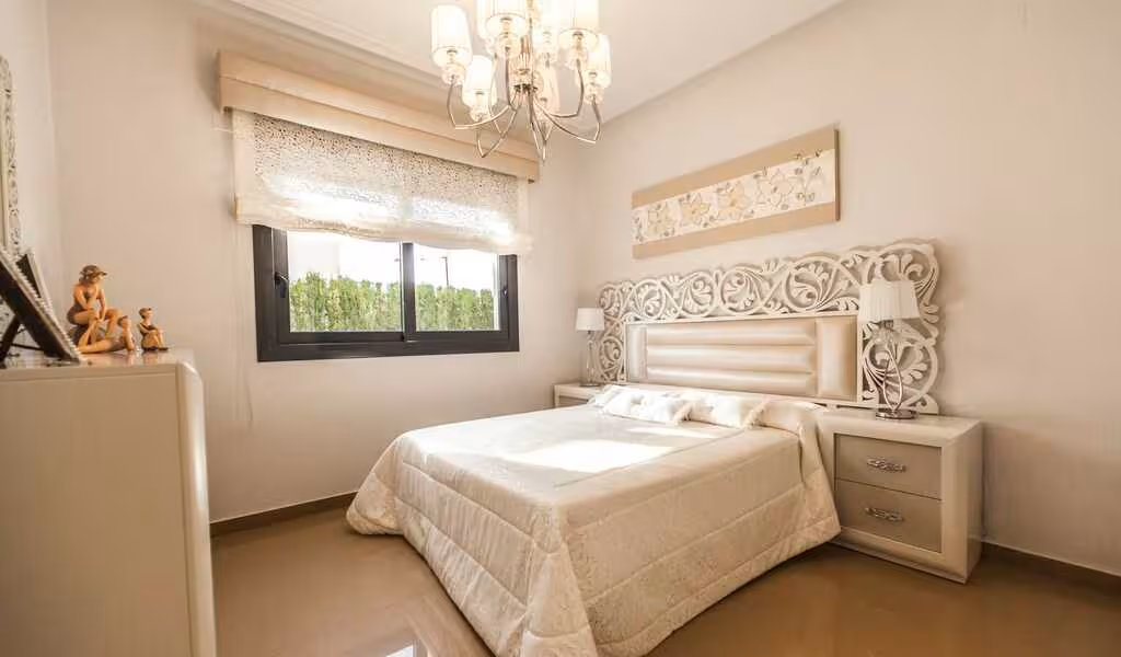A bedroom dimension showcasing a bed, comforter, and chandelier