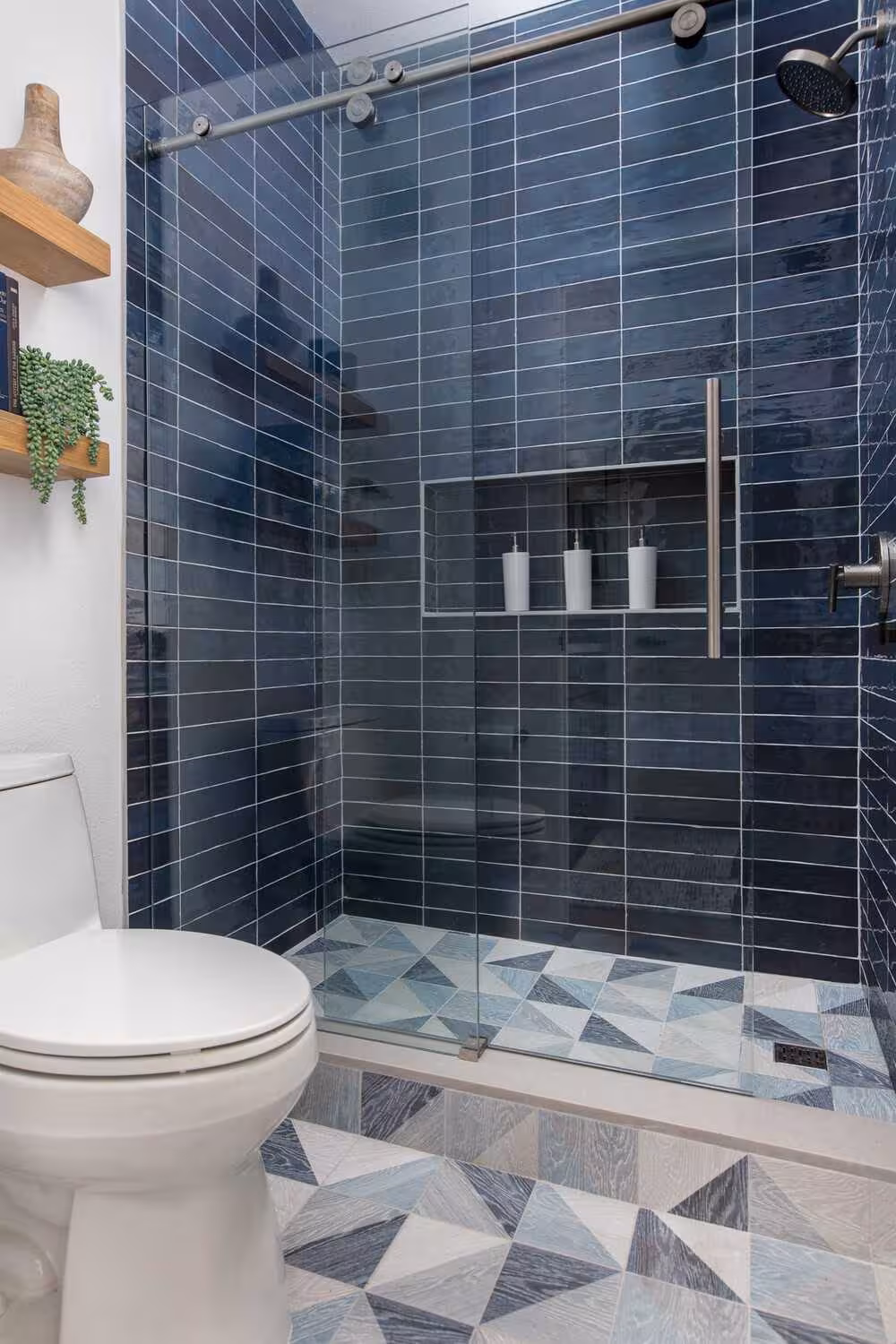 A blue tiled bathroom wall and a toilet system