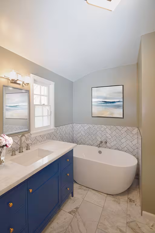 Blue bathroom vanity with a stone sink, a bathrub, and wall mirror