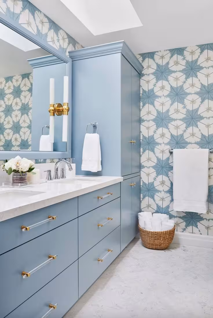 A bathroom with a light blue vanity and a towel hunged in a patterned wall