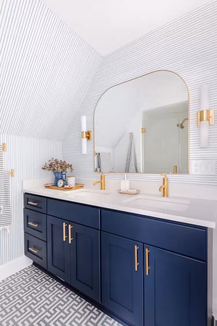 Cobalt blue bathroom vanity with gold hardware and a coordinating wallpaper design