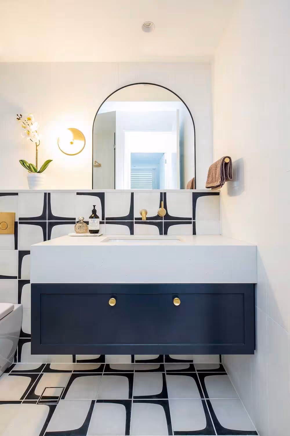 Dark blue bathroom vanity with a modern black and white porcelain tile backslash and a curved mirror