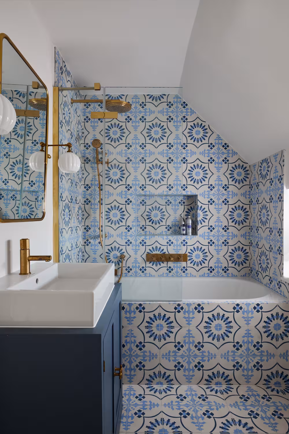 Mediterranean style navy blue cabinet bathroom design with a bathtub and brass fixtures