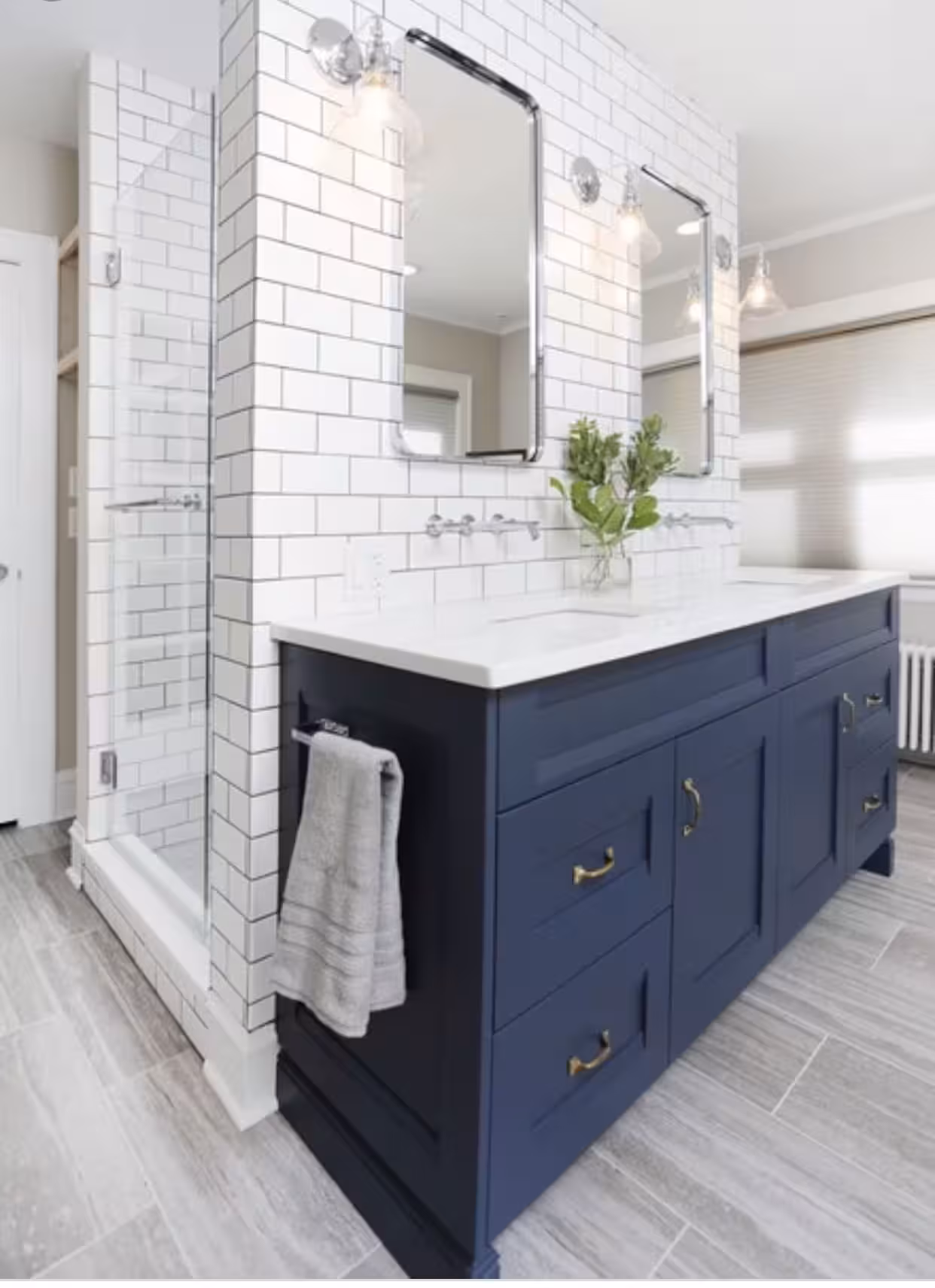 Navy blue bathroom vanity installed on a subway wall tiles with a flower sitting on the countertop