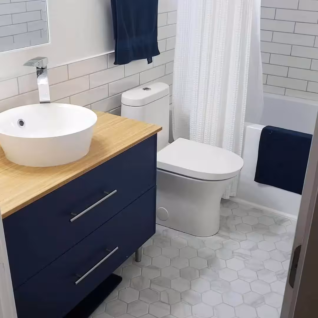 A blue bathroom vanity with a wooden countertop and a white sink ontop of the wooden countertop. A toilet sitting pretty by the side of the vanity