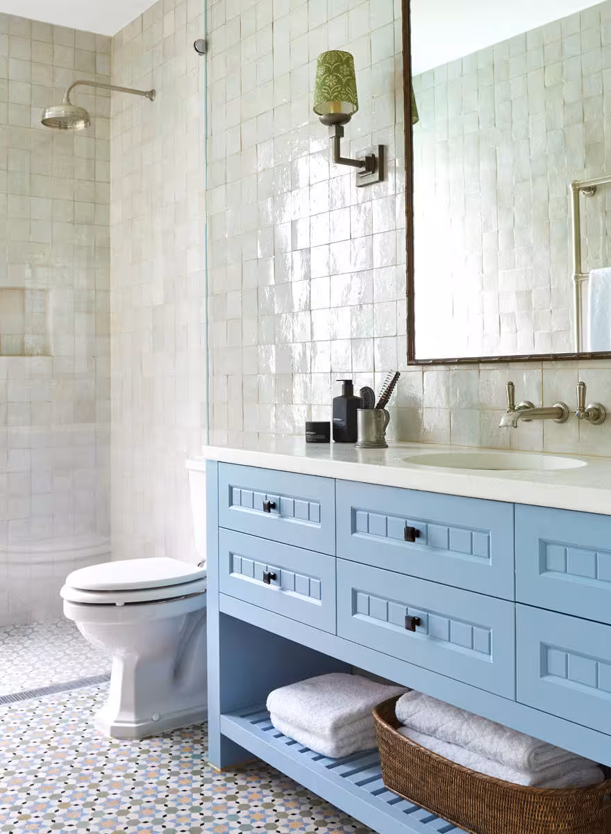 light blue bathroom vanity with a shinny porcelain wall tiles, a large mirrow and a water system