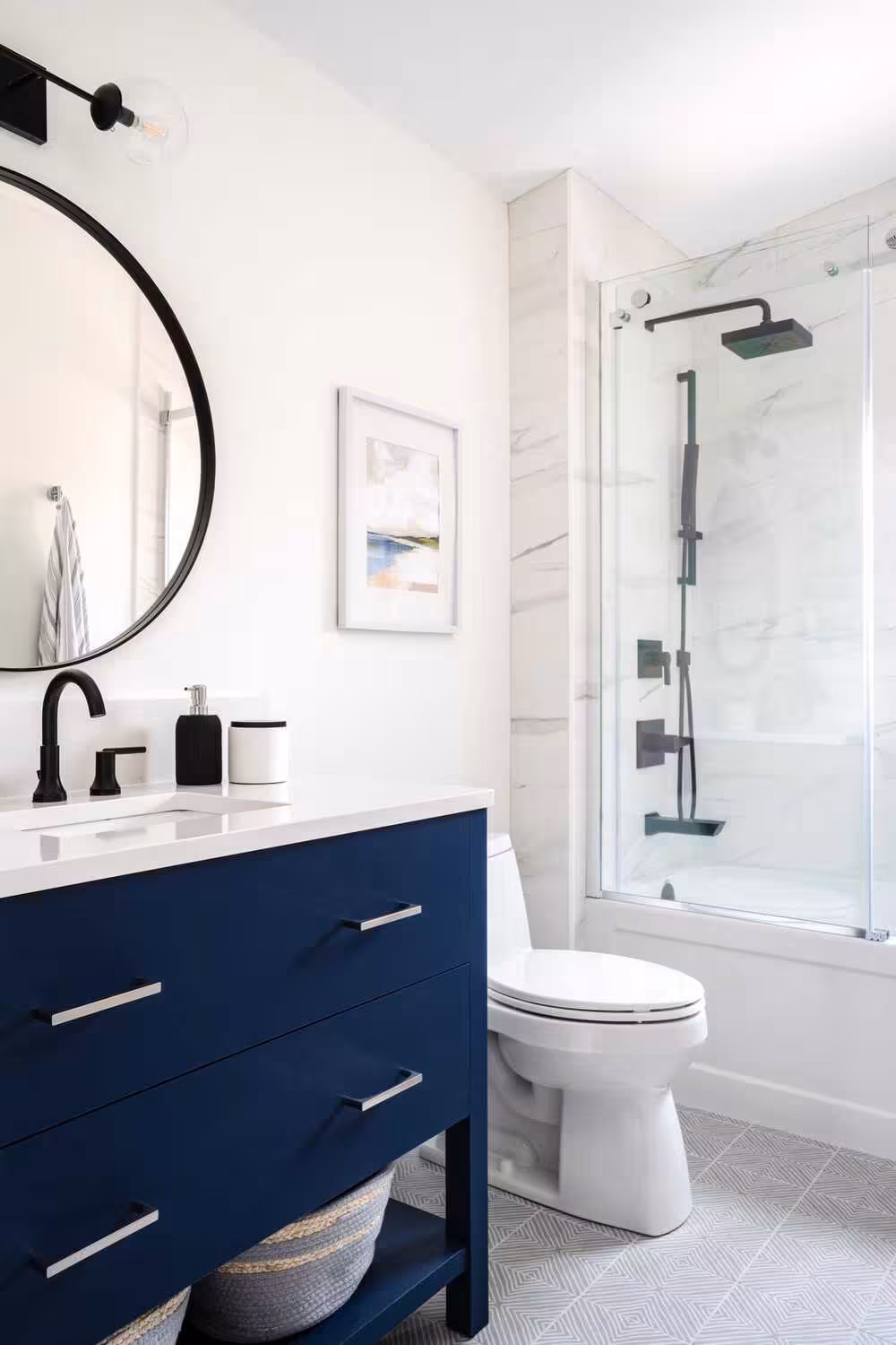 Traditional navy blue bathroom vanity ideas in a white bathroom space with round mirror and black faucet with toilet and white shower area