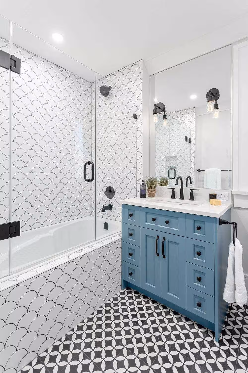Unique bathroom design with mermaid wall tiles, grout floor tiles and light blue bathroom vanity with white sink and black accent