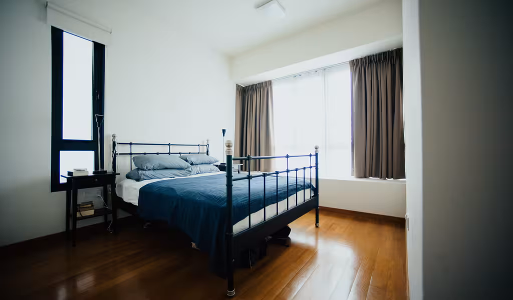 A bedroom with a bed and natural lightning showcasing the dimension of the bederoom