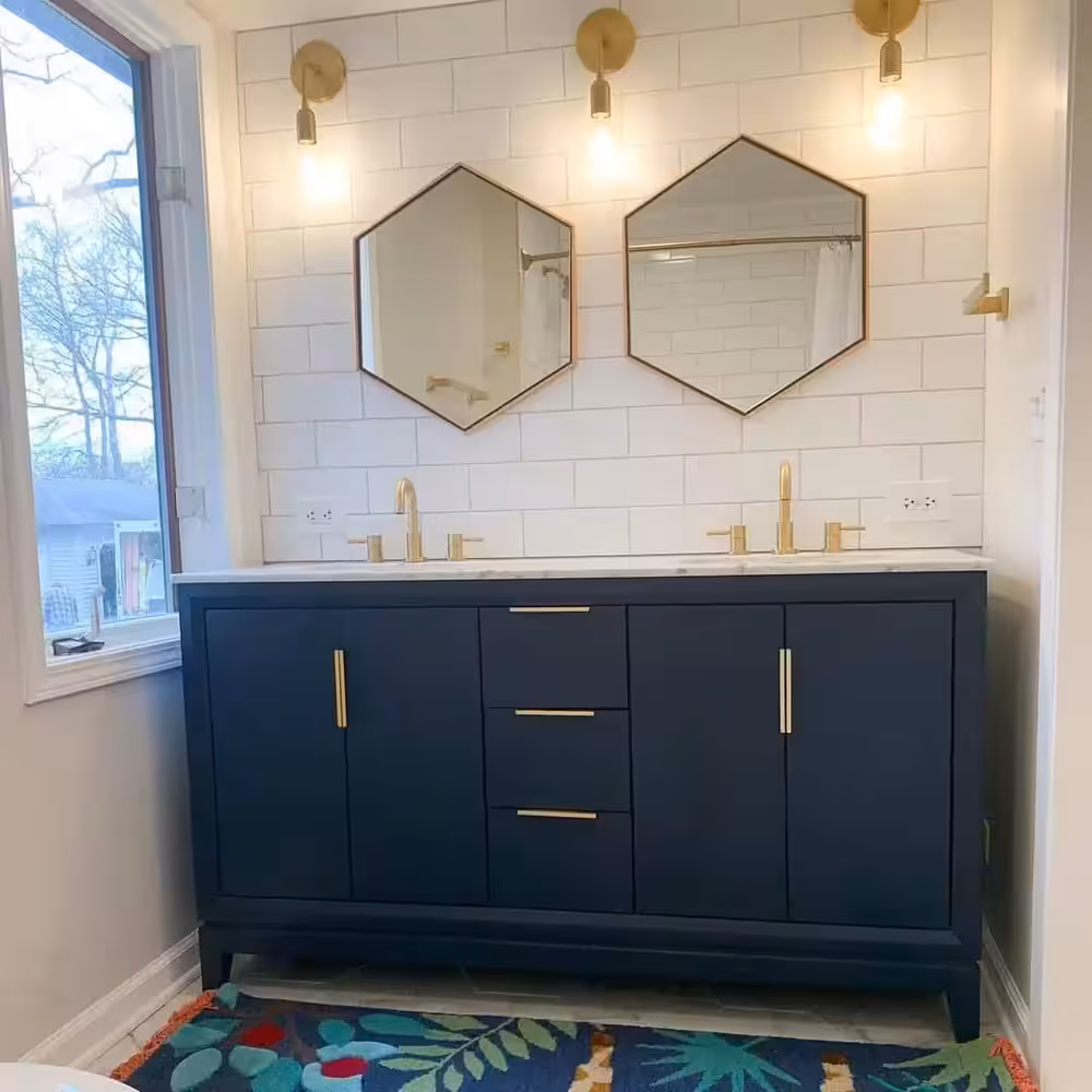 Navy blue bathroom vanity installed on a subway wall tiles with two hexagonal mirror and gold harwares
