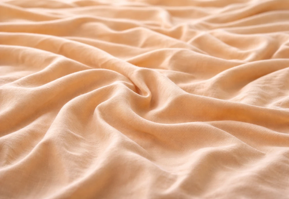 Orange Tencel bed sheets showing breathable eco-friendly fabric texture with smooth cooling surface.